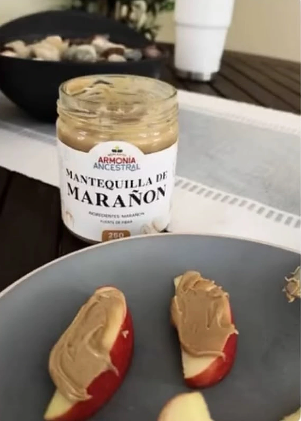 Rodajas de manzana con mantequilla de marañón y el frasco al lado